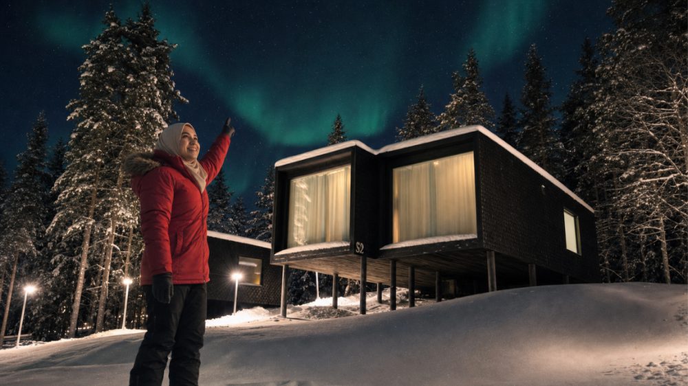 Malaysian traveller enjoying the Northern Lights beside her chalet at Arctic TreeHouse Hotel in Finland