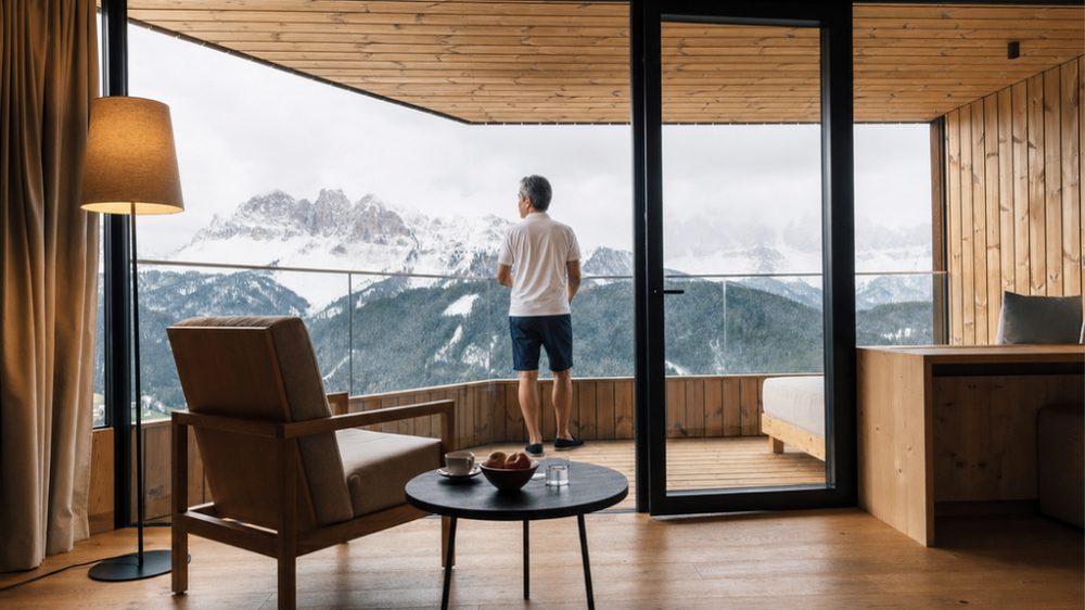 Man enjoying panoramic Dolomites views from his Forestis luxury hotel room in Italy